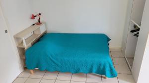 a room with a bed with a blue blanket at Proche de la plage, très bien situé in Ondres
