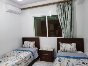 a bedroom with two beds and a window at Zemmouri in Tangier