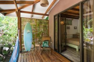 una tabla de surf sentada en una terraza junto a un dormitorio en Ohana Villas, en Santa Teresa Beach