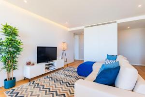 sala de estar con sofá blanco y TV en Pé n'Areia - Apartamento com Vista mar, en Praia da Barra