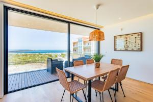 comedor con mesa y sillas y ventana grande en Pé n'Areia - Apartamento com Vista mar, en Praia da Barra