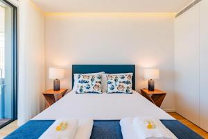 1 dormitorio con 1 cama grande y 2 lámparas en Pé n'Areia - Apartamento com Vista mar, en Praia da Barra