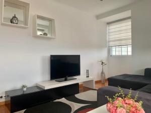 a living room with a flat screen tv on a white wall at Retiro das Bananeiras in Horta