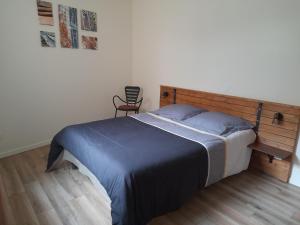 a bedroom with a bed with a wooden headboard and a chair at Gite des Cépages in Voiteur