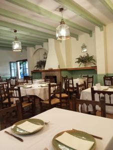 una sala da pranzo con tavoli bianchi e sedie in legno di Hospederia Casa de las Piedras a Grazalema