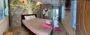 a bedroom with a bed with a painting on the wall at อีต่องโฮมสเตย์ in Thong Pha Phum