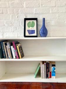 a shelf with books and a vase and a clock at Loft on Long in Hermanus