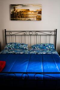 a bed with blue sheets and a painting on the wall at Praty Rooms in Rome