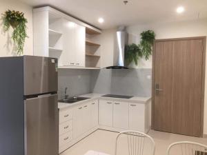 La cuisine est équipée de placards blancs et d'un réfrigérateur en acier inoxydable. dans l'établissement Nobita House toà S202 Vinhome Grand Park full nội thất view sông - Netflix, à Gò Công