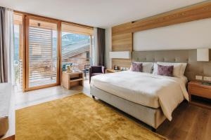 a bedroom with a large bed and a large window at Hotel Lajadira & Spa in Cortina dʼAmpezzo