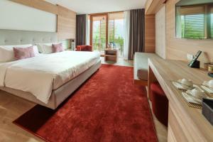 a bedroom with a large bed and a red rug at Hotel Lajadira & Spa in Cortina dʼAmpezzo