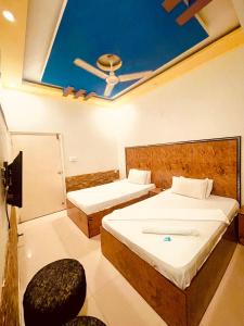 a room with two beds and a ceiling at Rehaish Inn in Karachi