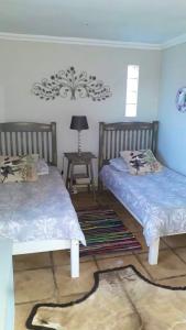 a bedroom with two beds and a table with a lamp at Kaltenbach Cottages in Magoebaskloof