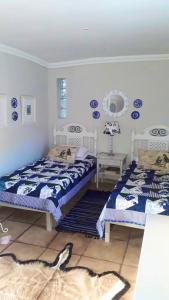 two beds in a room with blue and white at Kaltenbach Cottages in Magoebaskloof