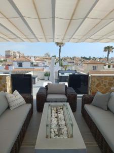 a patio with couches and a table on a roof at Luxury Villa with Heated Pool, Jacuzzi & Rooftop Lounge PMT22 in Torrevieja