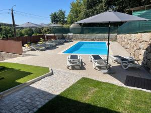 a swimming pool with lounge chairs and an umbrella at Casa do capitão A casa ideal para férias no Gerês in Vieira do Minho