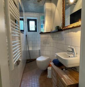 ein Badezimmer mit einem Waschbecken, einem WC und einem Spiegel in der Unterkunft HUUS UTSPANN FeWo mit Terrasse - 23 km vor Hamburg - in Seevetal