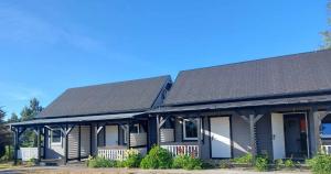 a house with a black roof and white doors at Domki Letniskowe Blue Sky 1 in Rewal