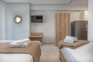 a room with two beds and a refrigerator at Sunshine Rooms and Suites in Nea Vrasna
