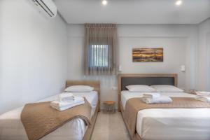- une chambre avec 2 lits et des serviettes dans l'établissement Sunshine Rooms and Suites, à Nea Vrasna