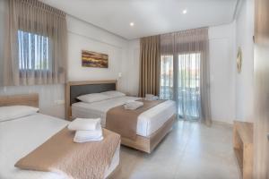 a hotel room with two beds and a balcony at Sunshine Rooms and Suites in Nea Vrasna
