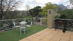 a patio with a table and a piano on a balcony at Pinewoods Rest in Somerset West