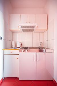 uma pequena cozinha com armários brancos e um lavatório em Apartmani Baki em Podstrana
