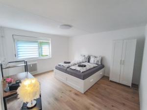 biała sypialnia z łóżkiem i biurkiem w obiekcie BeBu - Apartment w mieście Friedrichshafen