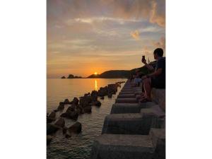 un gruppo di persone sedute su un molo a guardare il tramonto di HOMESTAY Kucha - Vacation STAY 17846v a Asa