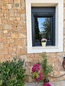 a window on a brick wall with two potted flowers at Kalisti Relax Villa in Nikiti