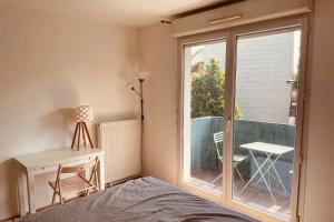 a bedroom with a bed and a window and a desk at Spacious 69 m nest with balcony in Aubervilliers