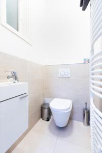 a white bathroom with a toilet and a sink at Bohéme Apartments Charle's Square in Prague