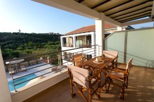 a balcony of a house with a wooden table and chairs at Michelangelo suites and apartments in Valanidorachi