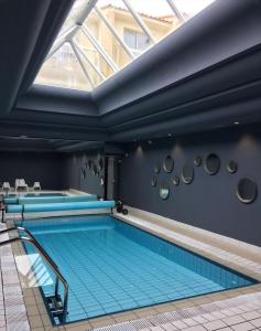 an indoor swimming pool with blue tiles on the floor and a window at Logis Hôtel Le Calluna Restaurant La Flottille in Préfailles