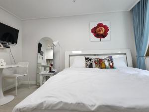ein weißes Schlafzimmer mit einem großen weißen Bett mit Kissen in der Unterkunft Welcome to Jejubi house in Jeju-do