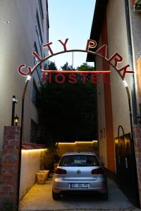 a car parked in front of a building with a sign at City Park Hostel in Pristina