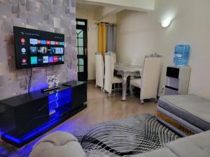 een woonkamer met een tv en een tafel en stoelen bij Cool Apartment Near all Embassies in Ruaka