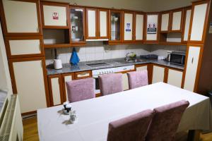 cocina con mesa blanca y sillas moradas en City Park Hostel en Pristina