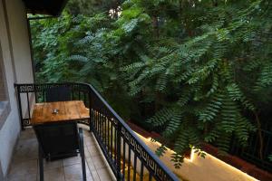 a balcony with a wooden table and a large green plant at City Park Hostel in Pristina