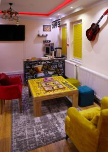 Sala de estar con mesa y guitarra en la pared en City Park Hostel en Pristina