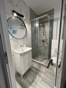 bagno con doccia, lavandino e specchio di Maison 25 a 2 Mai
