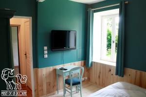 a bedroom with a bed and a tv on the wall at Maset de la Licorne in Nedde