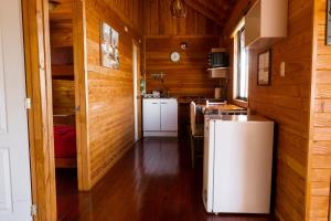 cocina con paredes de madera y nevera blanca en Cabañas Mirador Lago Ranco, en Lago Ranco