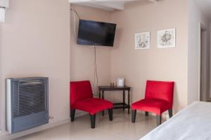 een kamer met twee rode stoelen en een tafel met een tv bij Cabaña de los Colibríes in Esquel