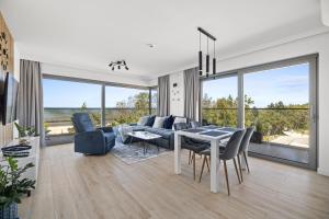 a living room with a table and chairs and a view of the ocean at Solaris Darłówko Premium Emilia Strupiechowska in Darłowo
