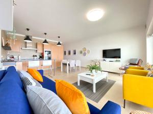 a living room with a blue couch and a kitchen at Deluxe 2 Bedroom Flat - BeachFront - Praia Del Rey in Amoreira