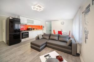 a living room with a couch and a kitchen at Centroom Pécs Apartman in Pécs