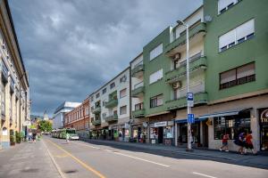 a city street with buildings and people walking on the street at Centroom Pécs Apartman in Pécs