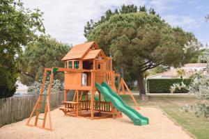 a wooden playground with a slide and a play house at Fleur de Sel in Noirmoutier-en-l'lle