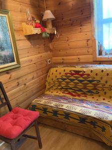 Schlafzimmer mit Holzwänden, einem Bett und einem Stuhl in der Unterkunft Chalet en bois à la Foux d'Allos in Allos